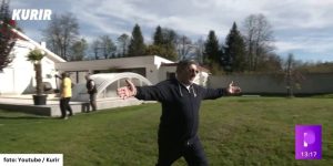A man with open arms walking across a lawn to greet his dog.
